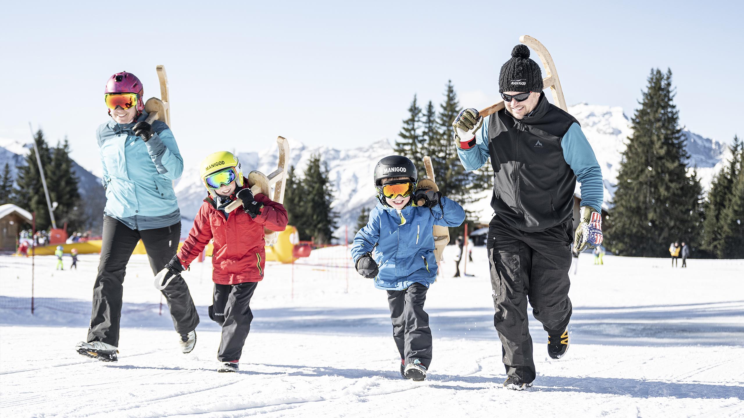 Une famille marche sur une piste du Grand-Bornand, leurs parets à la main