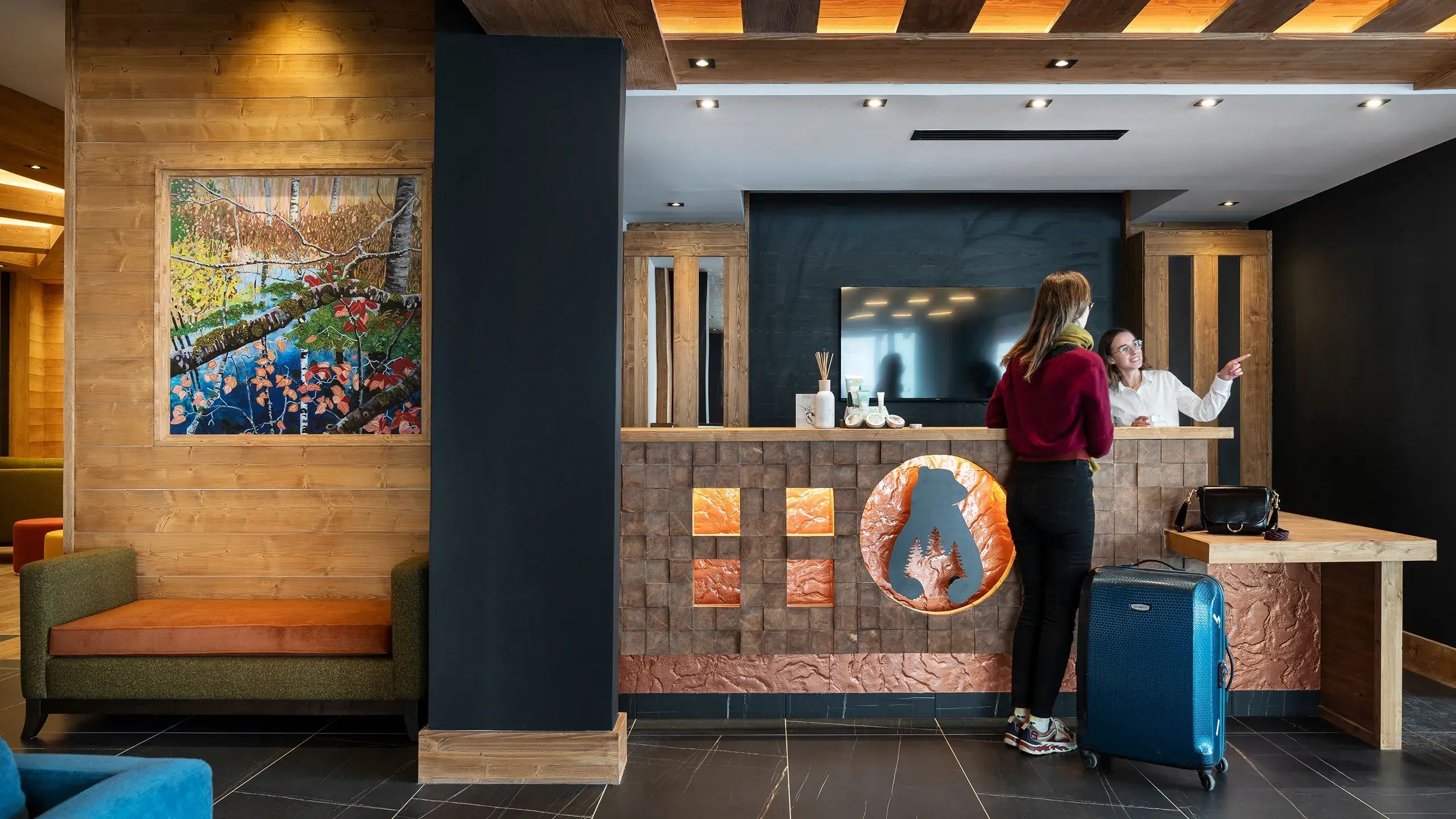 Une réceptionniste discute avec une client à la réception du Hameau de l'Ours à Manigod