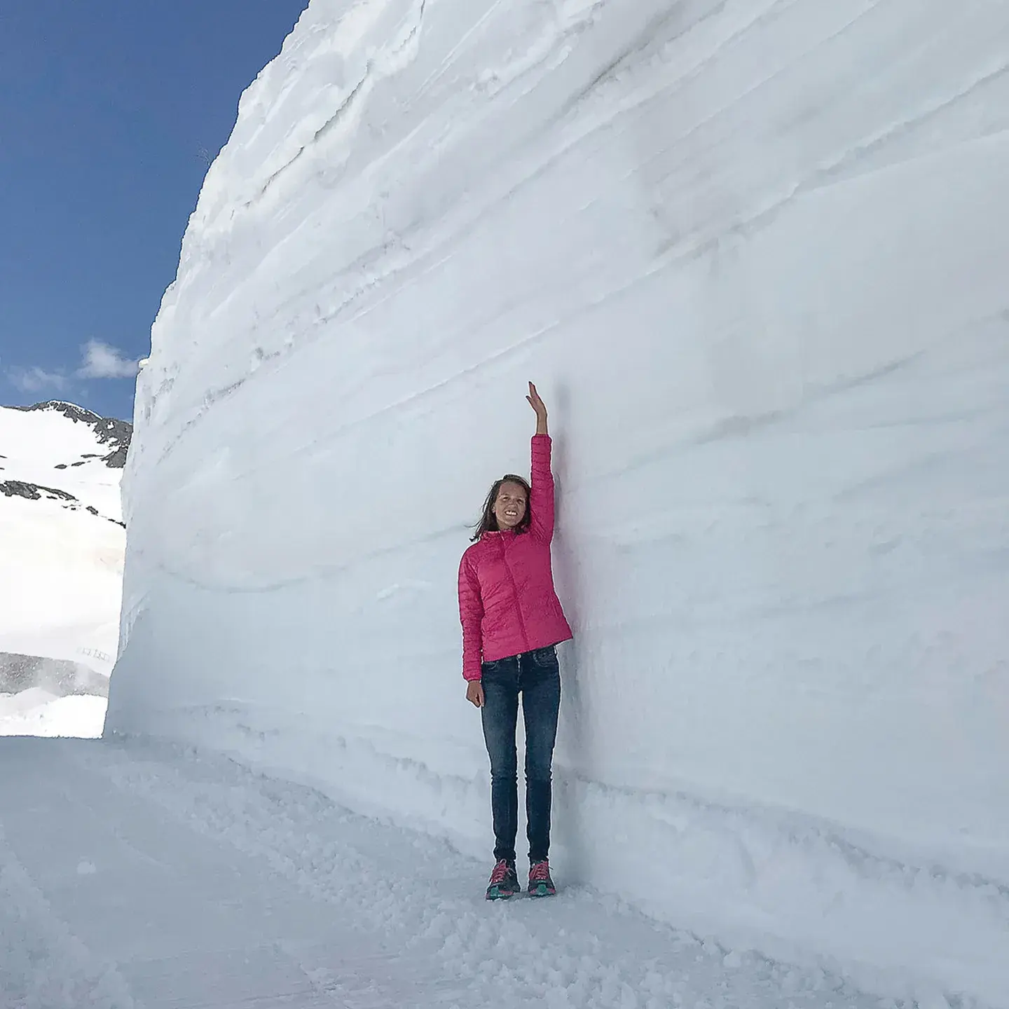 Une femme lève le bras pour montrer la hauteur de neige qui la dépasse du double de sa taille à La Rosière