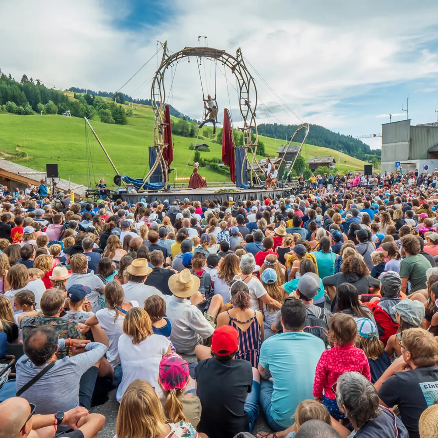 Une foule de spectateurs regarde 2 artistes effectués un spectacle de cirque  lors de l'évènement annuel aux Bonheur des Mômes au Grand-Bornand