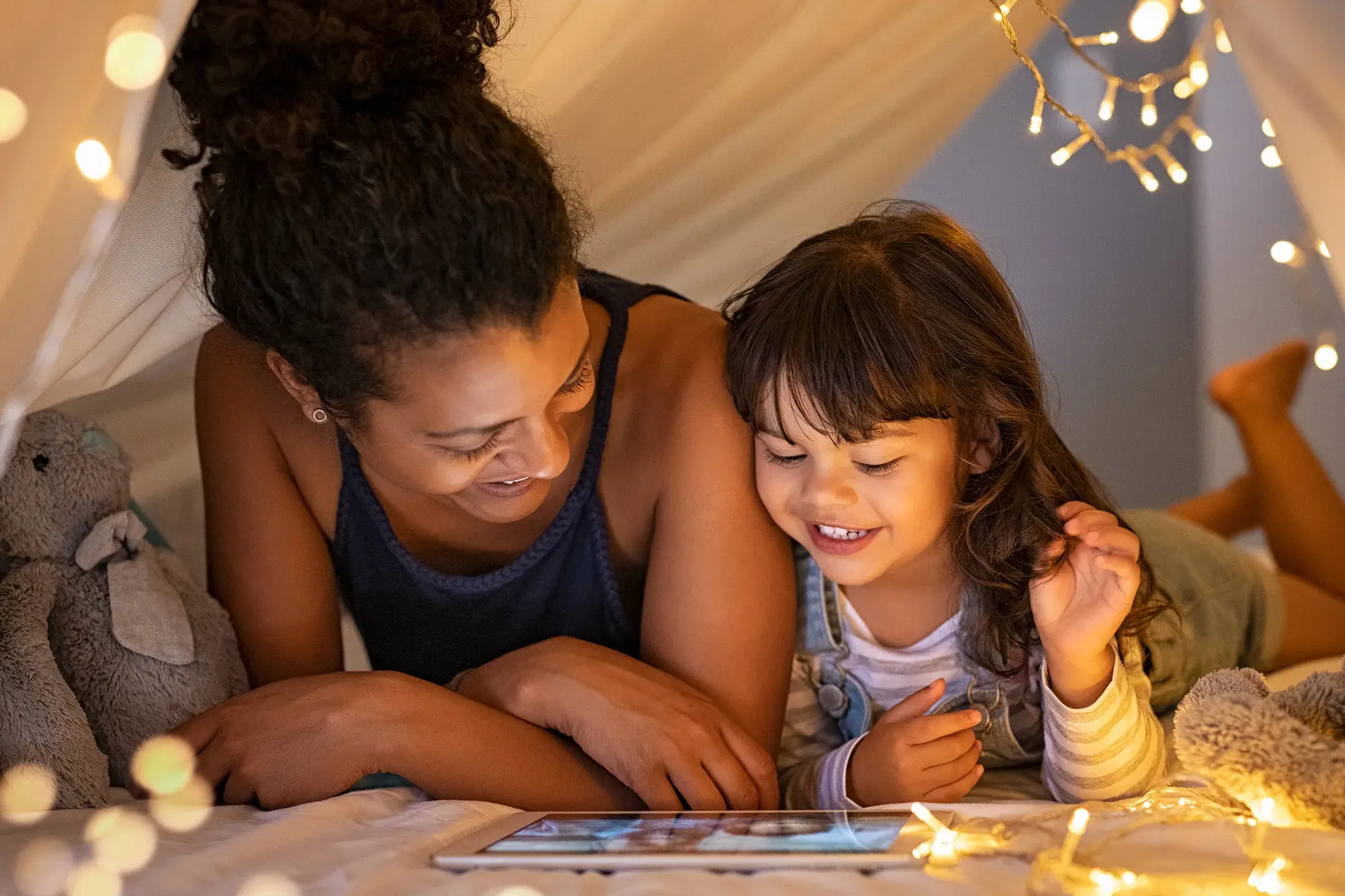 Femme et son enfant sous une cabane en drap avec guirlande 