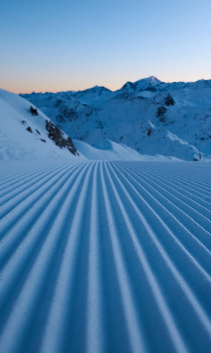 Traces dans la neige suite au passage d'une dameuse sur piste de Paradiski