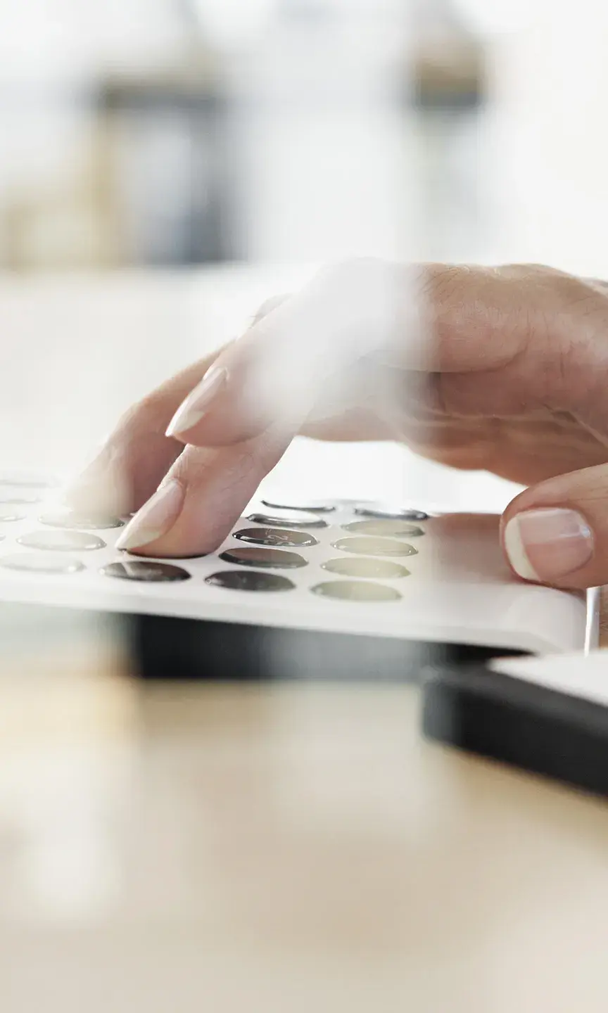 Gros plan sur la main d'une personne en train de faire des calculs grâce à sa calculette et un bloc notes