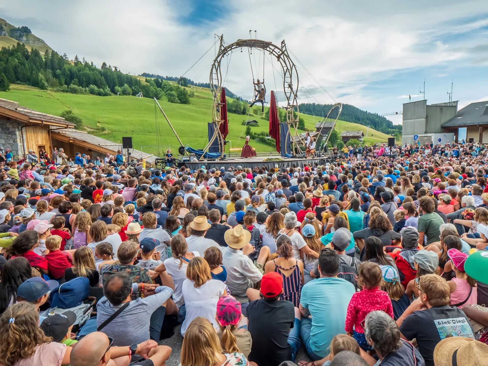 Une foule de spectateurs regarde 2 artistes effectués un spectacle de cirque  lors de l'évènement annuel aux Bonheur des Mômes au Grand-Bornand