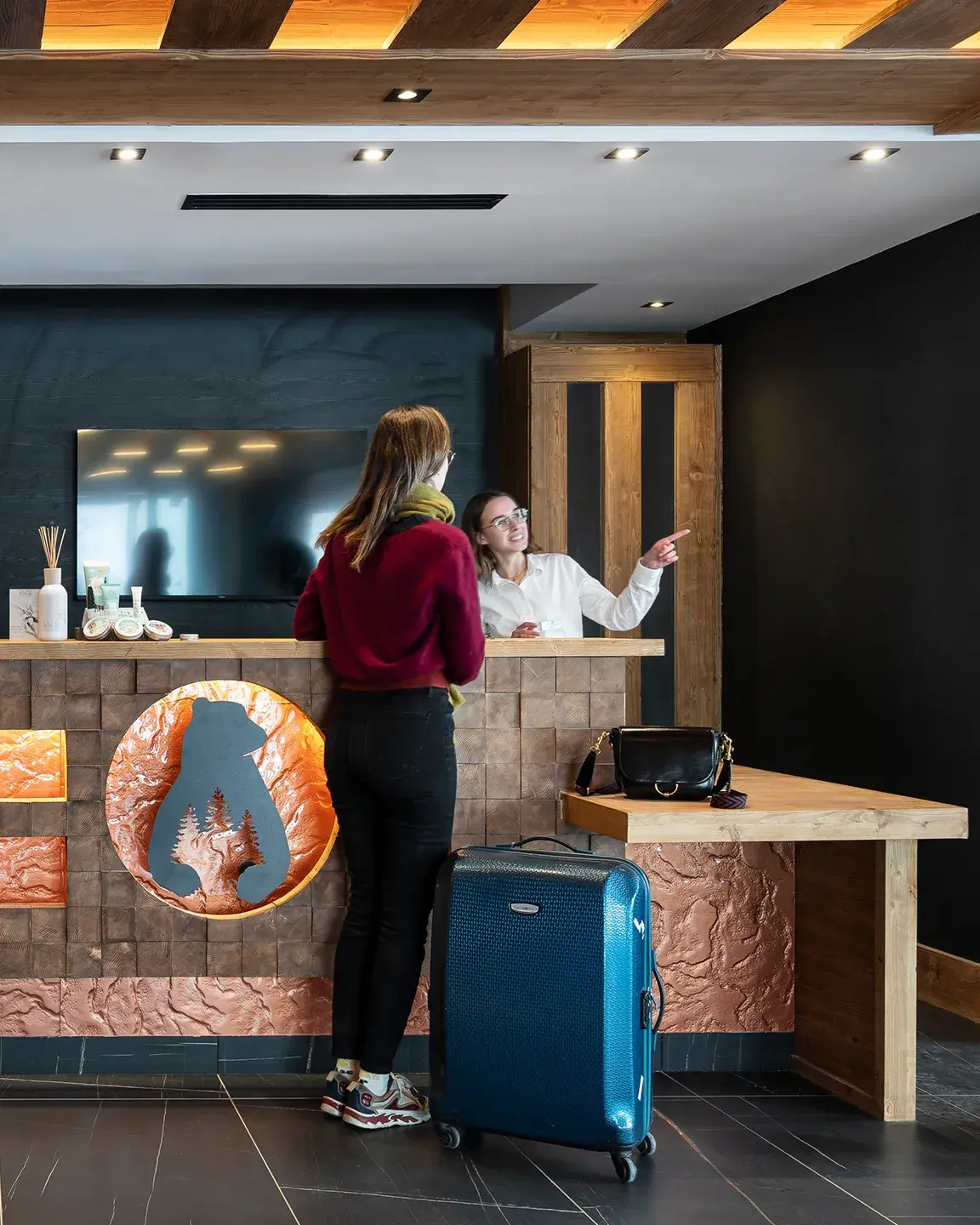 Une réceptionniste discute avec une client à la réception du Hameau de l'Ours à Manigod